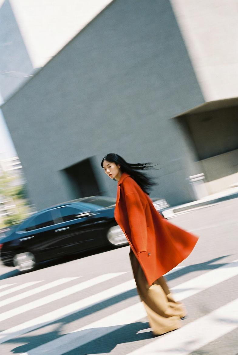 A candid street photography shot of a 25-year-old Asian female model with sharp 
