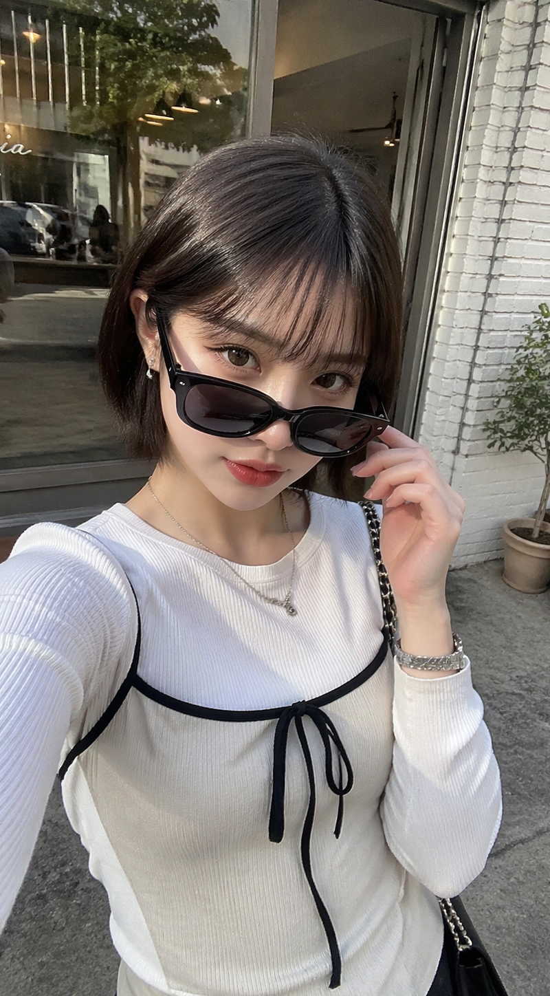 日本の若い20代の女性がカフェの前でiPhoneで自撮りした写真。ファッションは韓国風ファッション、ショートボブ、サングラスを少し下げてカメラを見ている。