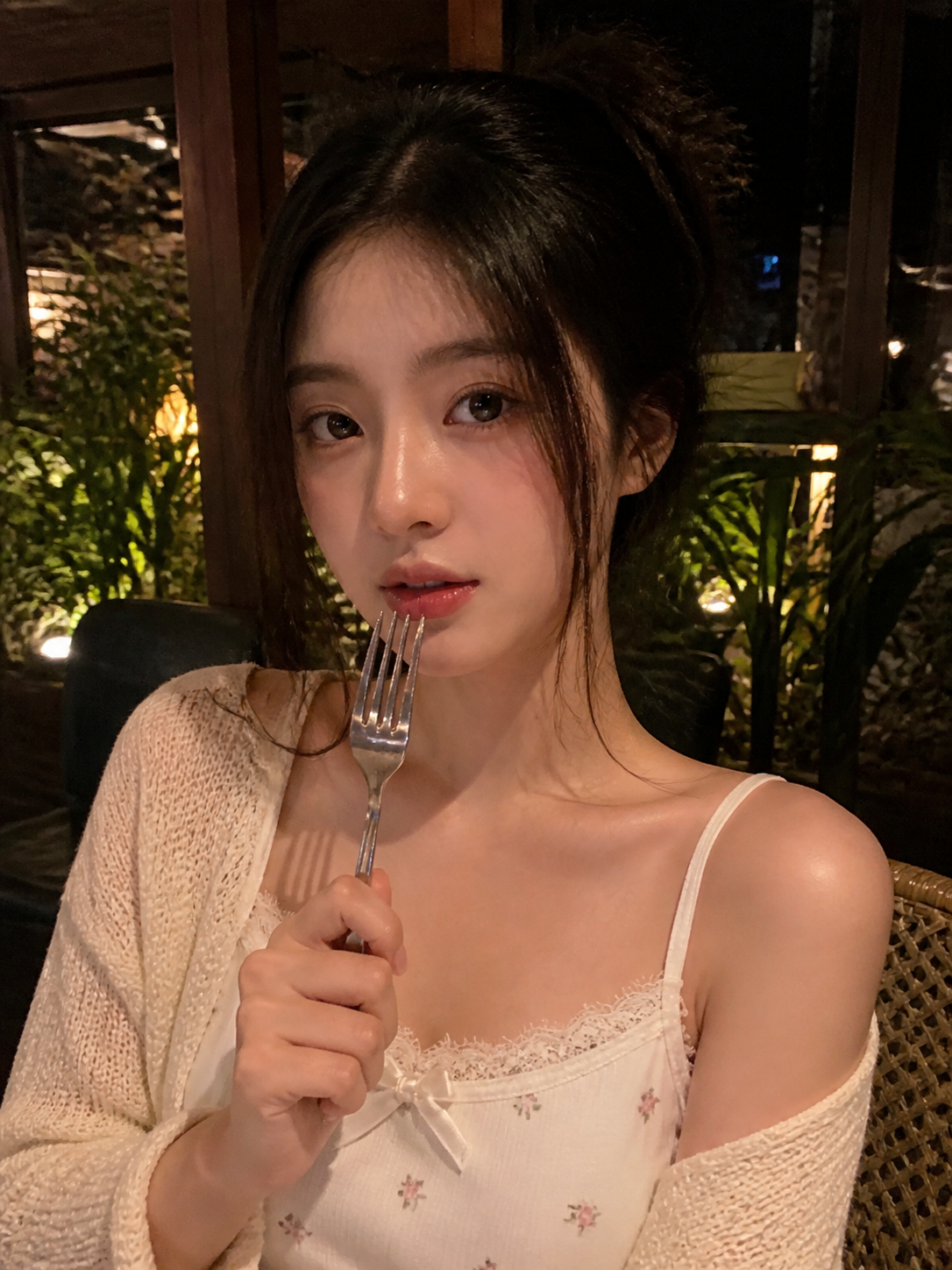 A realistic low-light smartphone restaurant portrait of a young adult woman sitt