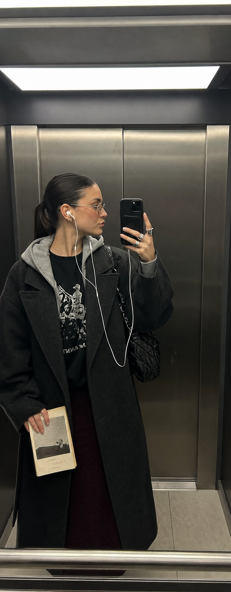 Ultra-realistic iPhone mirror selfie inside a sleek, dimly lit modern elevator, 