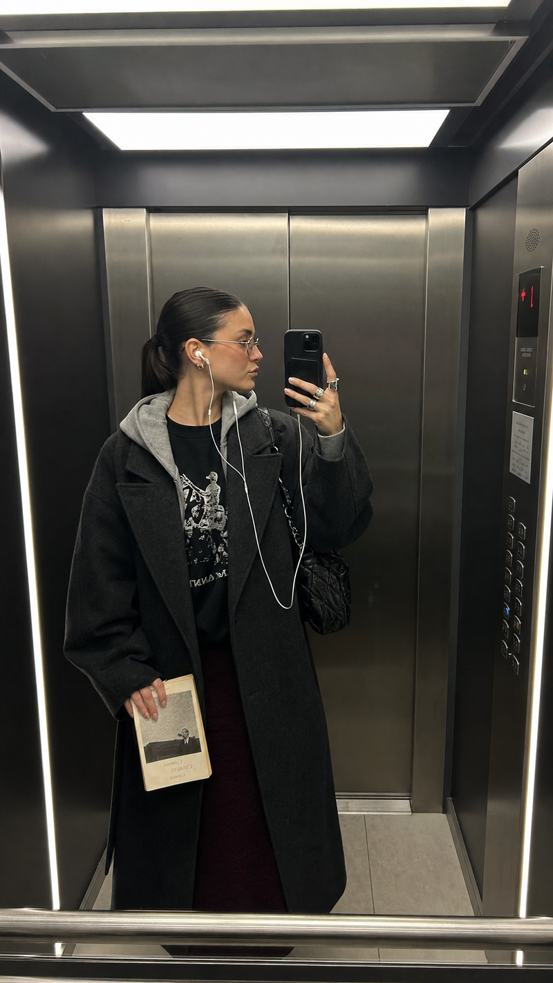Ultra-realistic iPhone mirror selfie inside a sleek, dimly lit modern elevator,