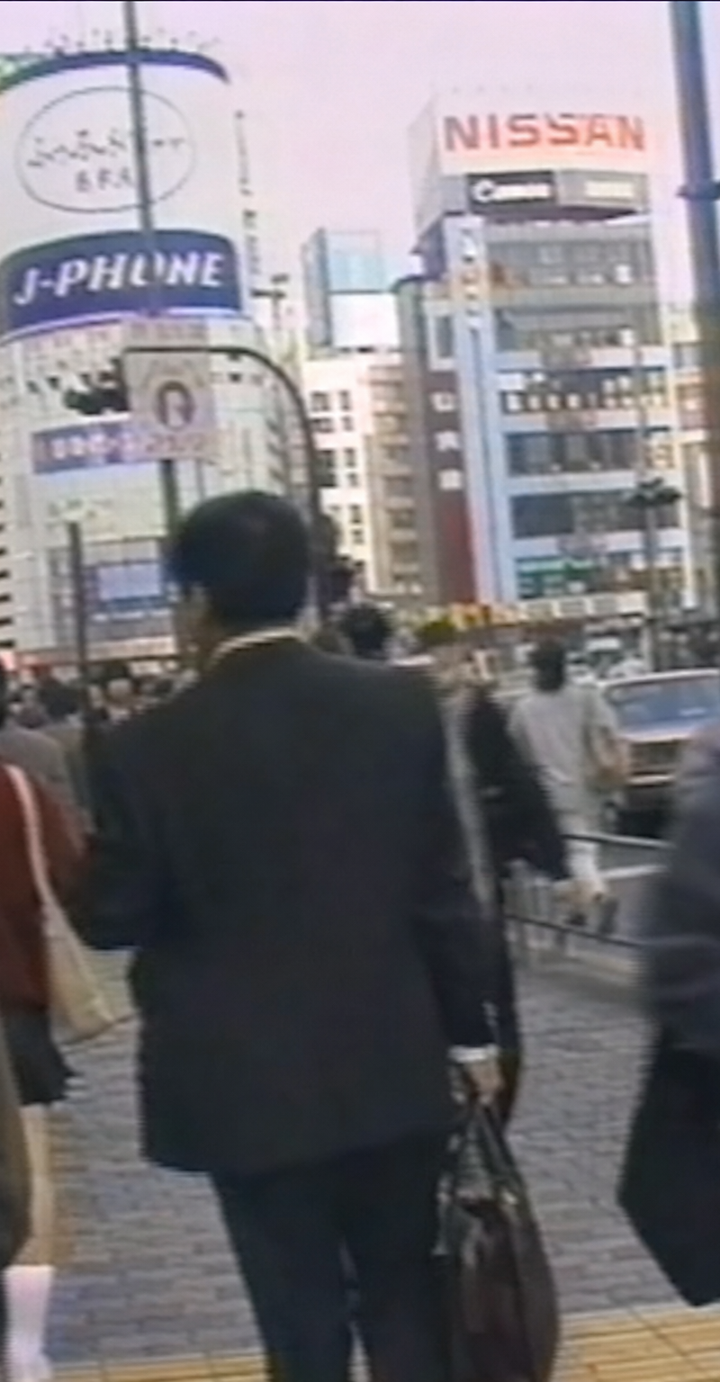 1990年の日本の渋谷を完全に再現した映像の1フレーム。 一人称視点で、渋谷の街を歩く人々を見ている。 画質や服装、広告、建物などは当時の日本の渋谷を完全に再現
