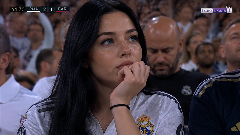 A high-definition, realistic broadcast shot of a young woman sitting in a crowde