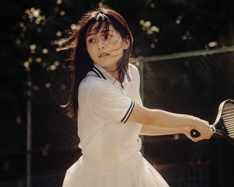 Cinematic middle shot of a Japanese teenage girl in tennis uniform, captured can