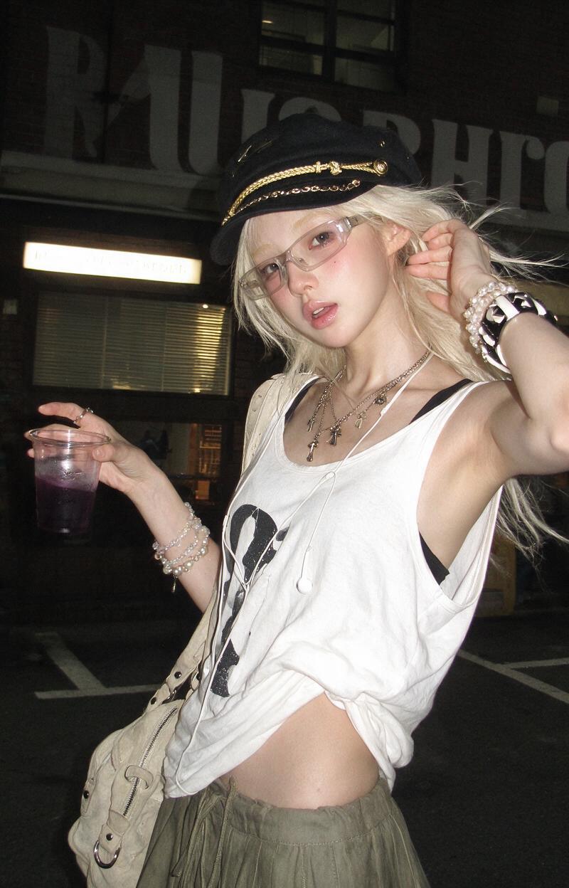 真实手机闪光灯夜间街拍,一位年轻成年女性站在街边 collection store / photo studio / cafe 门口,竖幅 3:4 构图,中近景