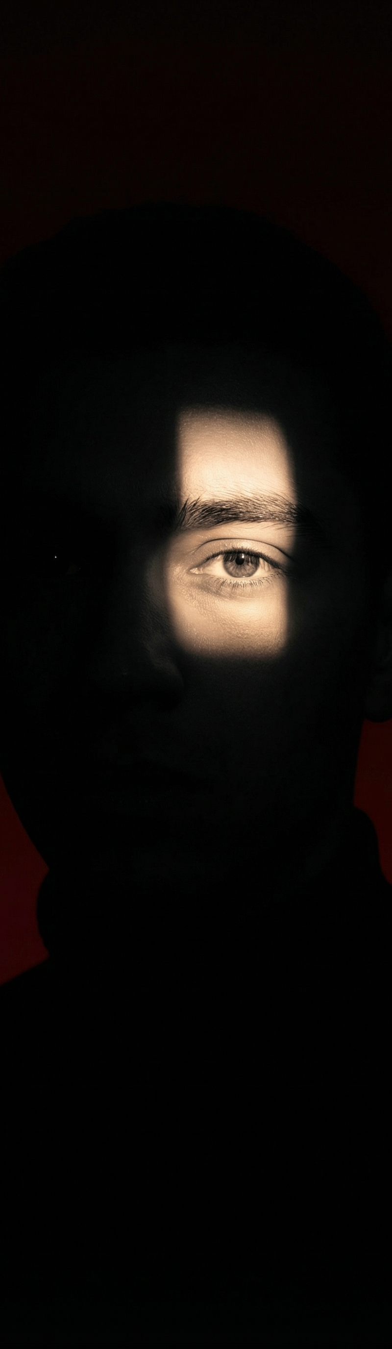 dramatic portrait where only one eye is illuminated through a narrow beam of lig