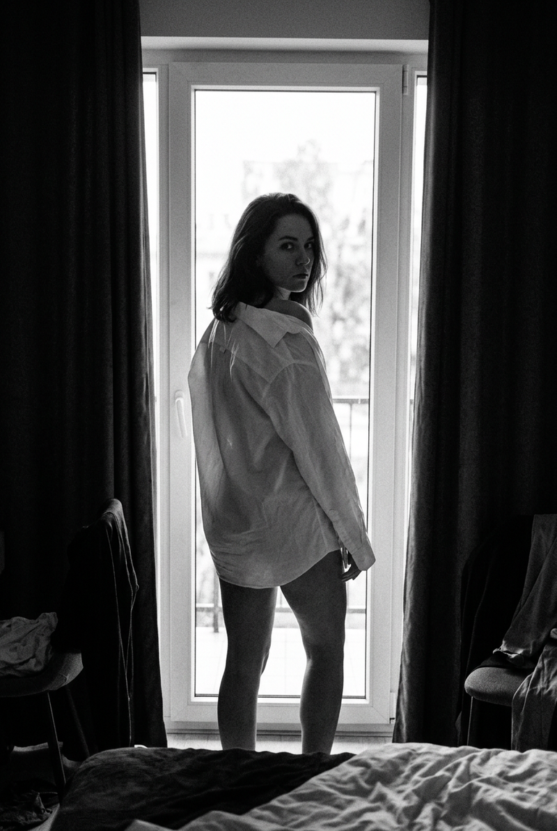 the woman in a black and white silhouette as she stands before a bright, windowe